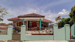 A two-story house with a tiled roof, a front porch, and a gated entrance. - OYO 3879 Villa Sari Intan (Ciater)