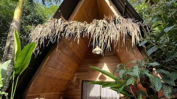 Una cabaña de madera con techo de paja, rodeada de exuberante vegetación.