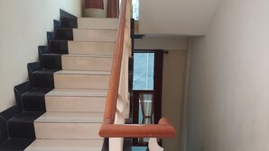 Una escalera con peldaños en blanco y negro, barandilla de madera y una puerta al final.