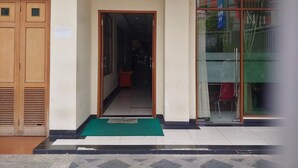 Entrada de hotel con puerta de madera, felpudo verde y suelo de baldosas.