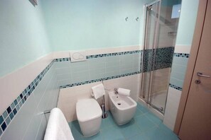A bathroom with a toilet, bidet, and shower.
