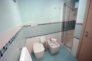 A bathroom with a toilet, bidet, and shower.