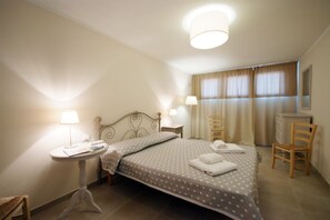 A hotel room with a bed, bedside table, lamp, chair, and a desk with a chair. - Located just 200 meters from Procchio’s main street and about 600 meters from the beautiful sandy beach, this spacious four-room apartment is the ideal choice for anyone looking for a comfortable and relaxing vacation just a few minutes’ walk from the sea (Procchio)