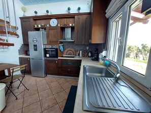 Une cuisine avec des meubles en bois, un évier en acier inoxydable et une horloge au mur.