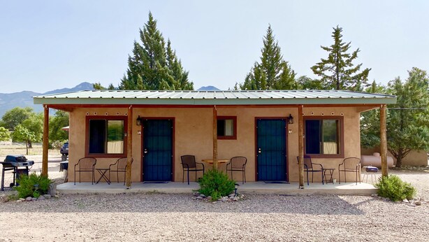 A small, single-story building with a flat roof, two front doors, and a patio area with outdoor seating.