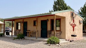 A small, single-story building with a porch, outdoor seating, and a small table.