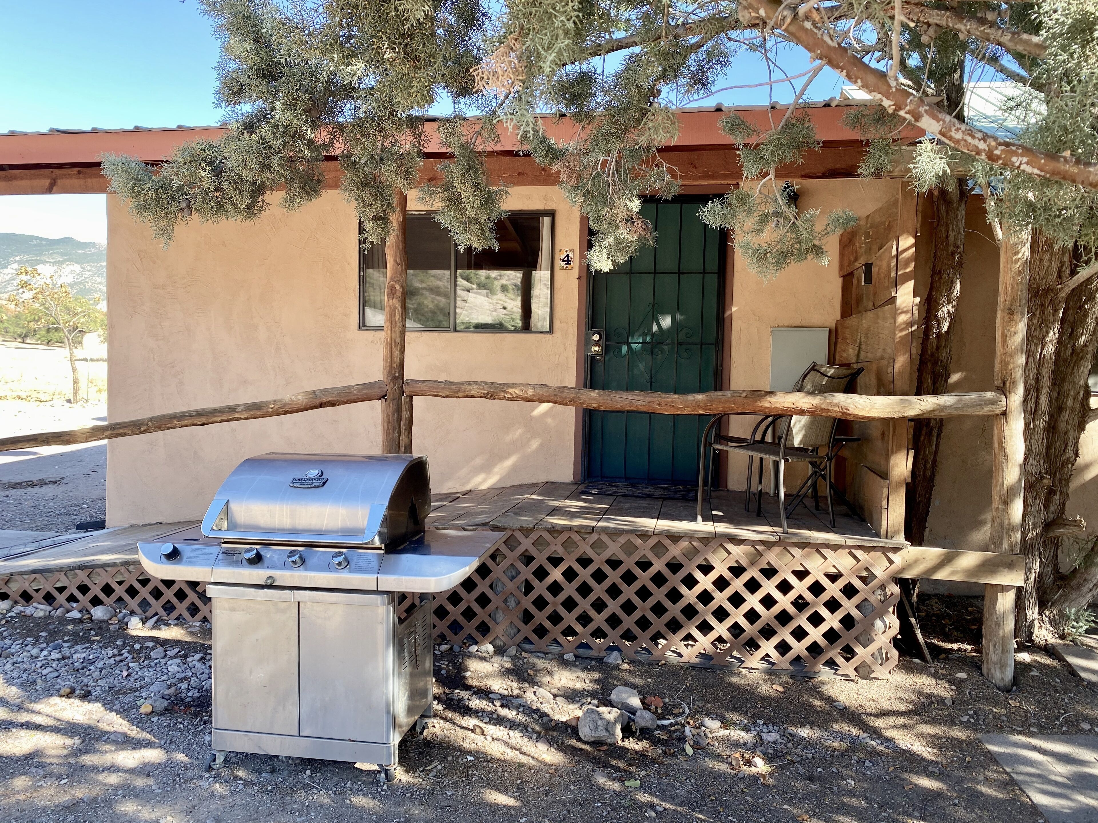 A patio with a barbecue grill, a wooden table, and a chair.