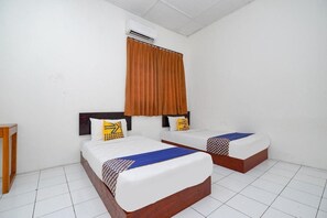 Una habitación de hotel con dos camas, una mesita de noche de madera, una ventana con cortinas marrones y un equipo de aire acondicionado.