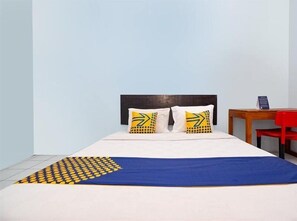 Una cama con un edredón azul y dos almohadas con un estampado amarillo y verde.