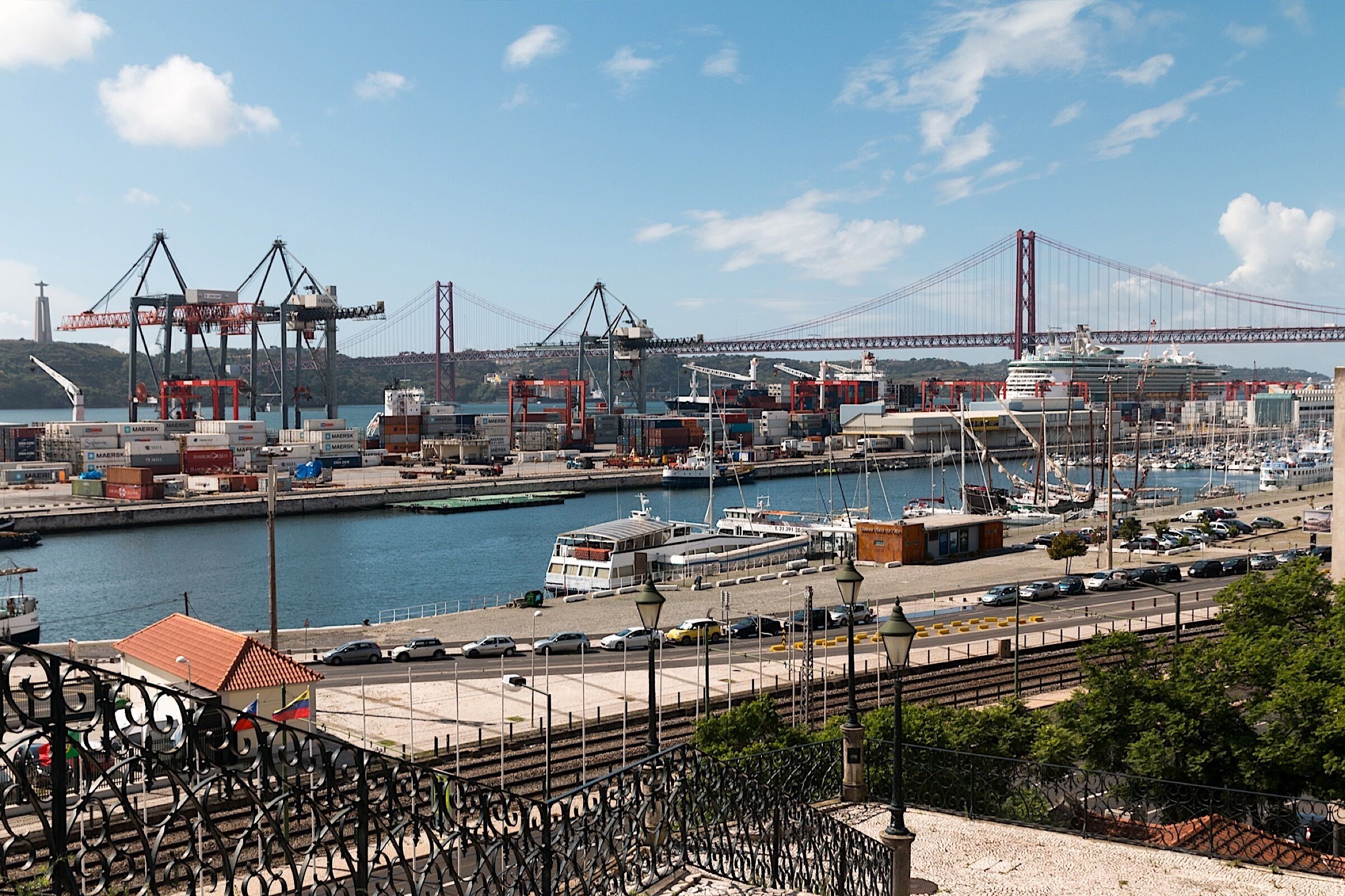 A harbor with a large bridge, shipping containers, and a marina with boats.