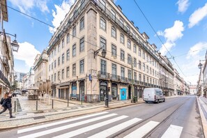 Vista de la calle con un edificio que tiene una farmacia en la planta baja y una puerta azul.