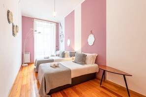 Un dormitorio con dos camas, un radiador, una lámpara de pie y una mesita.
