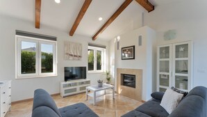 Ein modernes Wohnzimmer mit grauem Sofa, Flachbildfernseher und Kamin.