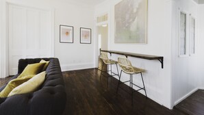 A modern living room with a dark sofa, two framed pictures, and a large abstract painting on the wall.
