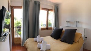 Ein Hotelzimmer mit einem Bett, zwei Nachttischlampen, einem Fernseher und einem Fenster mit Vorhängen.