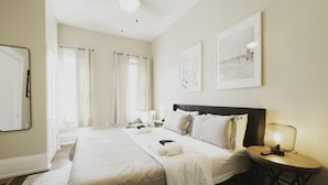 Ein Hotelzimmer mit einem großen Bett, einem Nachttisch mit Lampe und zwei gerahmten Bildern an der Wand.
