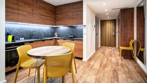 Une cuisine moderne avec des meubles en bois, un plan de travail noir et une table ronde en bois, assortie de chaises jaunes.