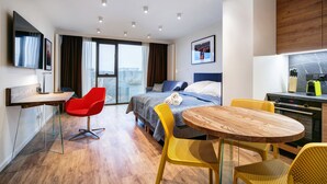 Une chambre d’hôtel moderne équipée d’un lit, d’un bureau, d’une table à manger et d’un coin cuisine.