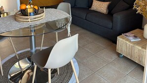 Ein modernes Wohnzimmer mit einem Glastisch, einer Couch und einem kleinen Beistelltisch.