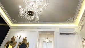 A room with a grand chandelier, ornate mirrors, and a fireplace. - Portuguese Soul Bica | Iconic Tram View & Patio | Sleeps 4 (Lisboa)