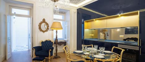 A dining area with a chandelier, a round table set for four, and a bar area with a mirror.