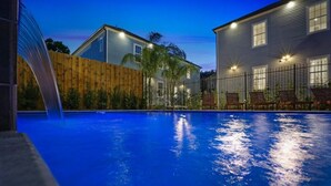 Una piscina con una valla de madera y una casa al fondo.