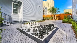 A residential area with a large outdoor chessboard set up on a paved patio.