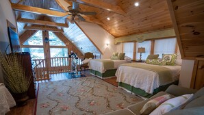 Una habitación acogedora con dos camas, un ventanal grande y techo de madera.