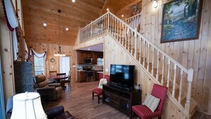 Un salón espacioso con una escalera de madera, un televisor y una zona de comedor.