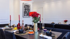 Une table à manger dressée avec des assiettes, des verres et un vase rempli de roses rouges.