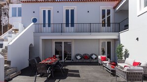 Un bâtiment à deux étages doté d’un balcon, d’un espace extérieur aménagé pour s’asseoir et d’un escalier menant à l’étage supérieur.