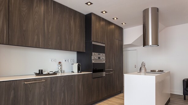 Une cuisine moderne avec des meubles en bois foncé, des appareils électroménagers en acier inoxydable et un îlot central.