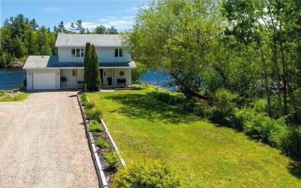 A two-story house with a front porch, a driveway, and a well-maintained lawn. - Georgian Bay Riverside Retreat (Britt)