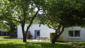 A house with a white exterior, a blue door, and a window. There is a wooden table and a bench in the front yard. - MORGAT 70 meters Beach, 8 people with garden and parking (Crozon)
