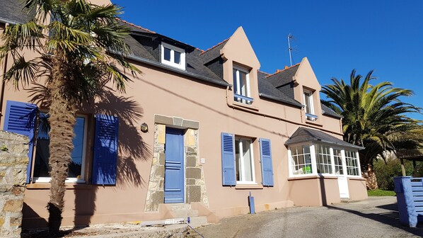 A two-story building with blue shutters, stone accents, and a clear blue sky.