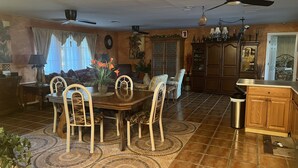 A spacious dining area with a wooden table and chairs, a kitchen with wooden cabinets, and a ceiling fan. - Gorgeous waterfront Spanish villa with heated pool on beautiful oversized canal! (Cape Coral)