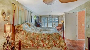 Een slaapkamer met een bed, een plafondventilator, een nachtkastje en een lamp.