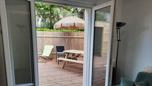 A sliding glass door leading to an outdoor patio with a wooden deck, a thatched umbrella, and a picnic table. - House on the seafront, beach 150 m away  (Île-Tudy)
