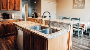 A kitchen with wooden cabinets, granite countertops, a double sink, and a coffee maker. - Charming Home North Logan 3BD/2.5BA Sleeps 6 (North Logan)