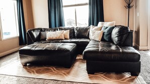 A living room with a sectional sofa, a floor lamp, and a large window with curtains. - Charming Home North Logan 3BD/2.5BA Sleeps 6 (North Logan)
