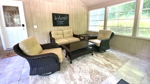 A cozy room with a beige sofa, two wicker chairs, a small table, and a chalkboard sign that reads "Welcome, May all who enter, as guests, leave as friends." - 30 min from Notre Dame + Hottub, 10 acre estate and game room (Edwardsburg)