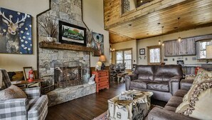 A cozy living room with a stone fireplace, leather sofas, and rustic decor. - Mountain River Lodge by Mountain Oasis | River View Cabin in Ellijay (Ellijay)