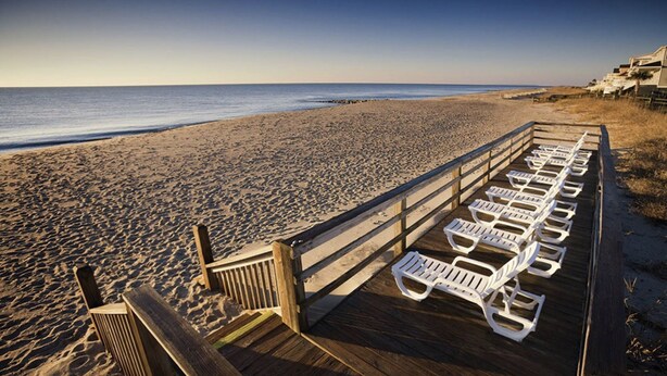 A wooden boardwalk with white lounge chairs along the beach. - Edisto 2BR W/Resort Amenities and beach access (Edisto Island)