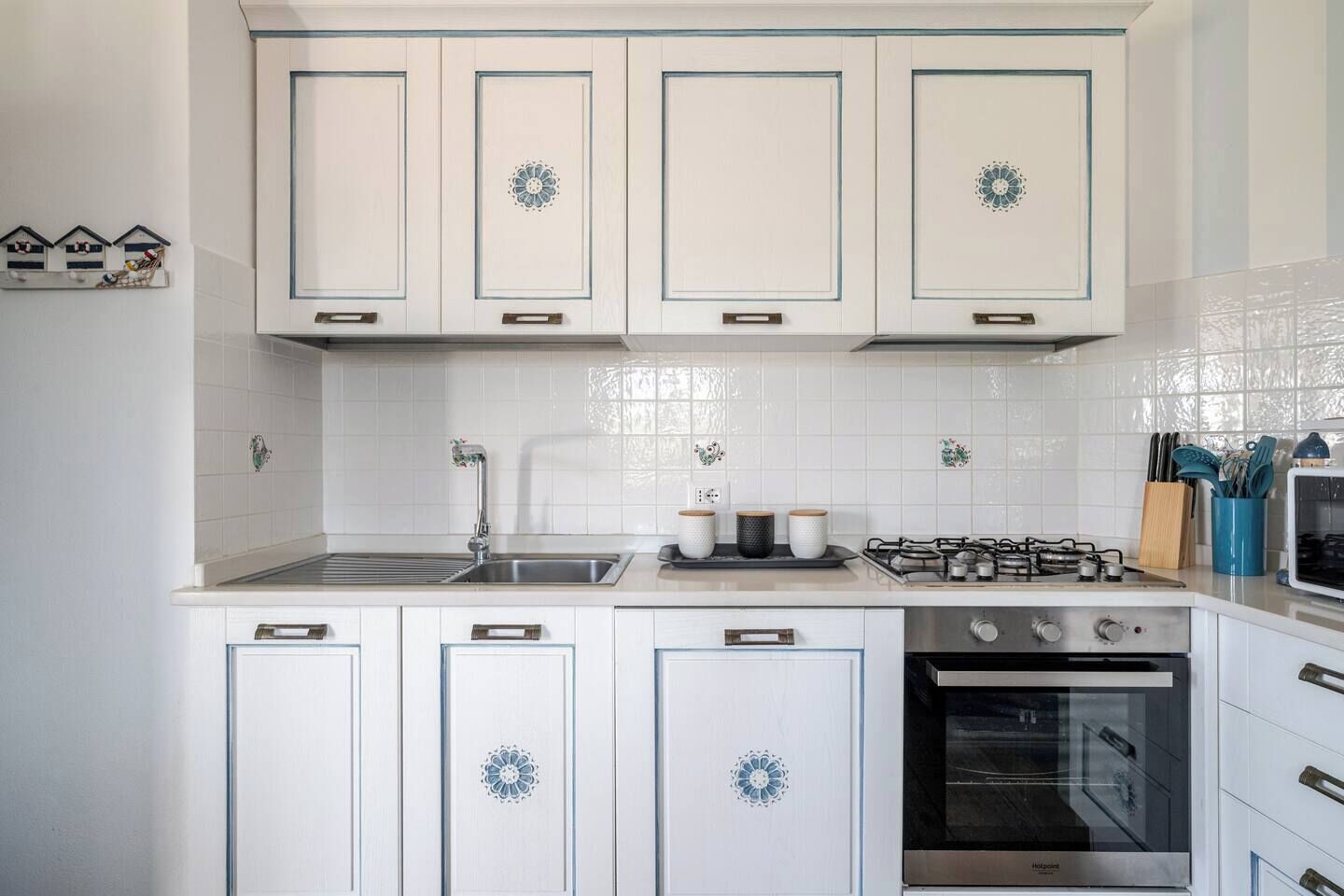 A kitchen with white cabinets, a gas stove, a sink, and a dishwasher.