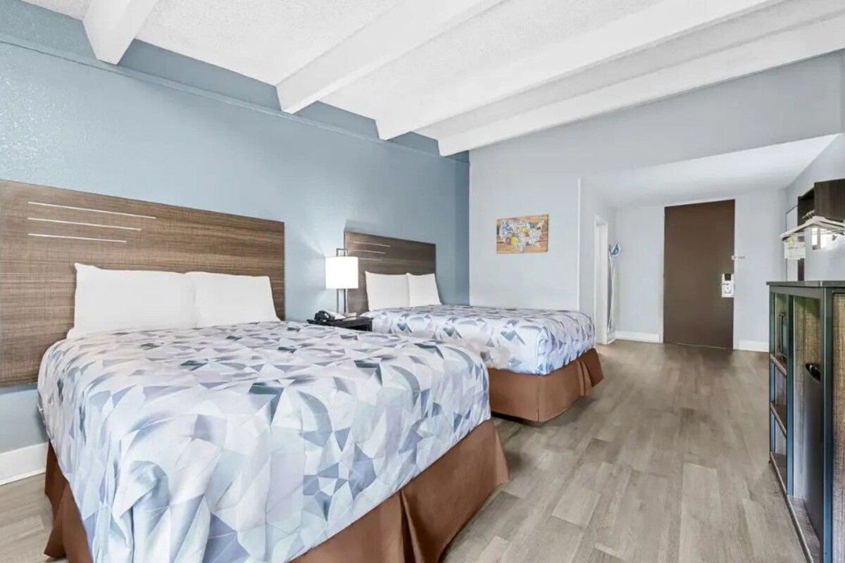 A hotel room with two beds, a wooden headboard, a desk, and a cabinet.