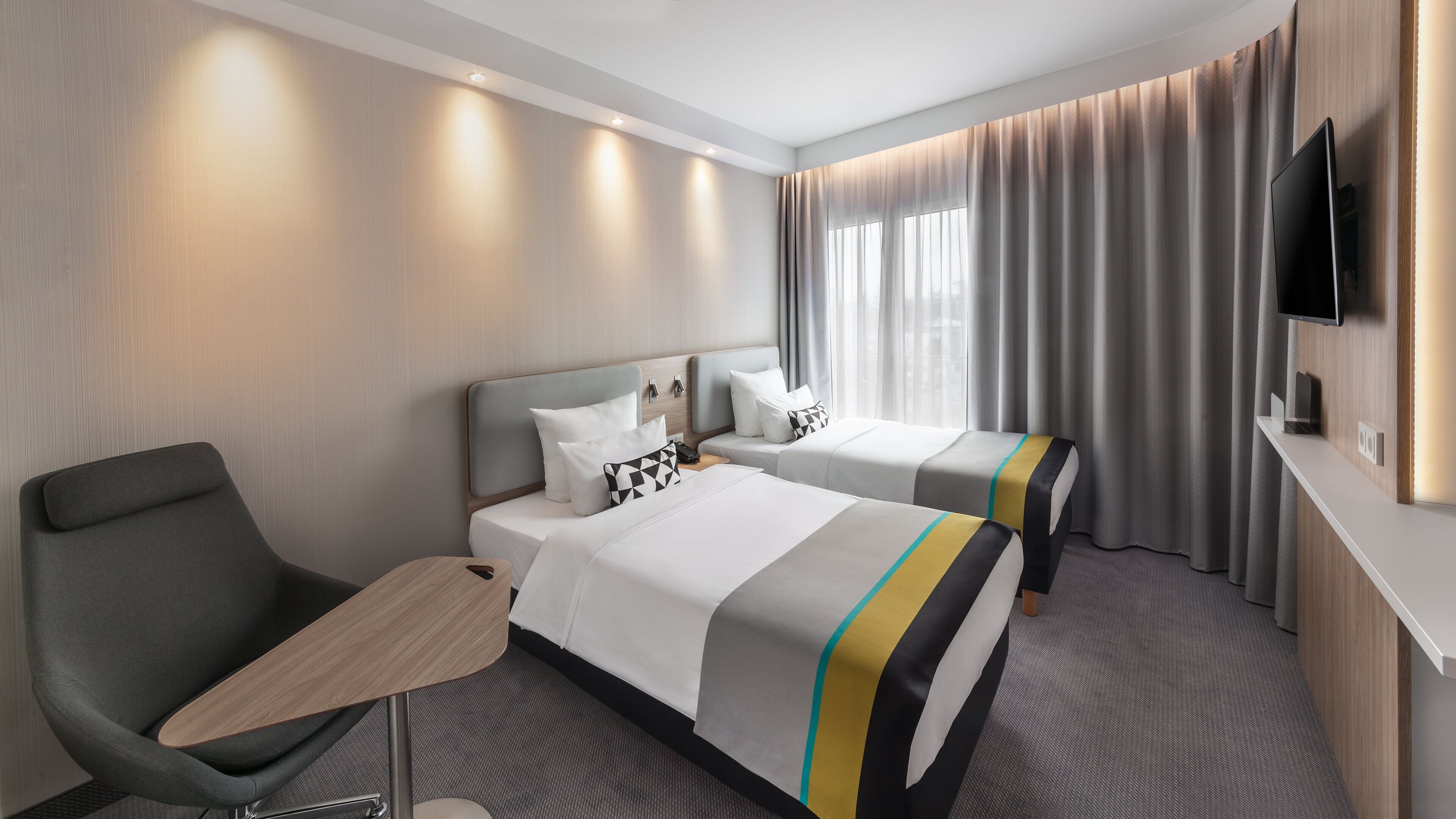 Une chambre d’hôtel avec deux lits, un bureau, une chaise et un téléviseur.