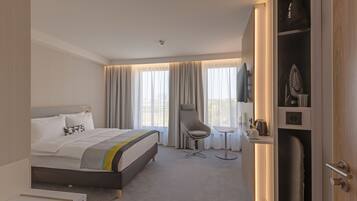 Una habitación de hotel con una cama, una silla, una mesita y un armario.