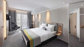 Una habitación de hotel moderna con una cama grande, un escritorio, una silla y un televisor.
