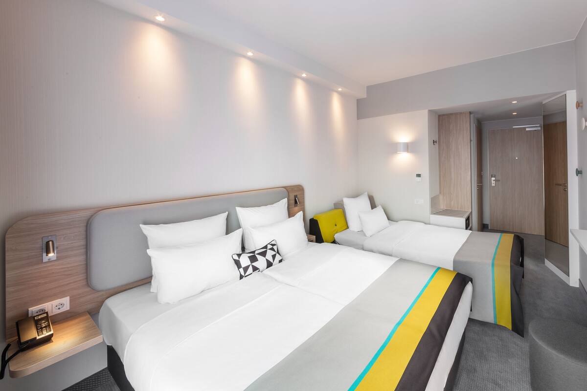Ein Hotelzimmer mit zwei Betten, einem Fernseher und einem Schreibtisch mit Steckdose.