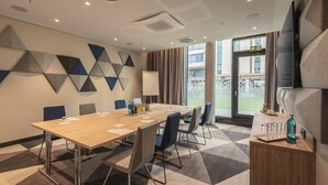 A modern conference room with a wooden table, chairs, and a whiteboard. - Holiday Inn Express Düsseldorf – Hauptbahnhof by IHG (Düsseldorf)